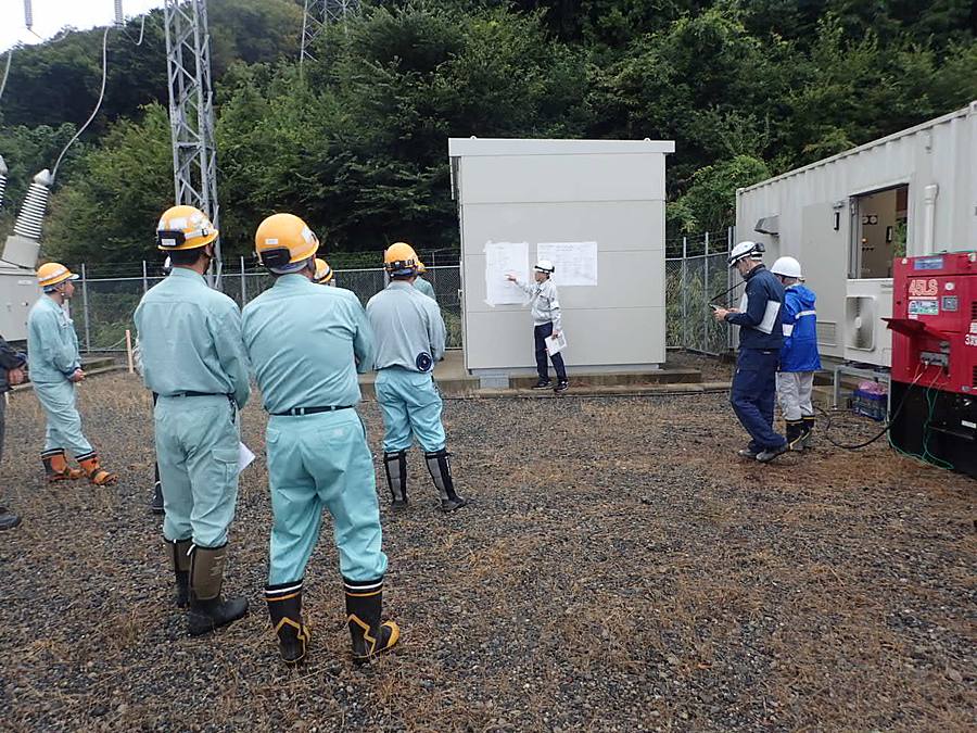 作業場でホワイトボードを前に安全朝礼を行う様子