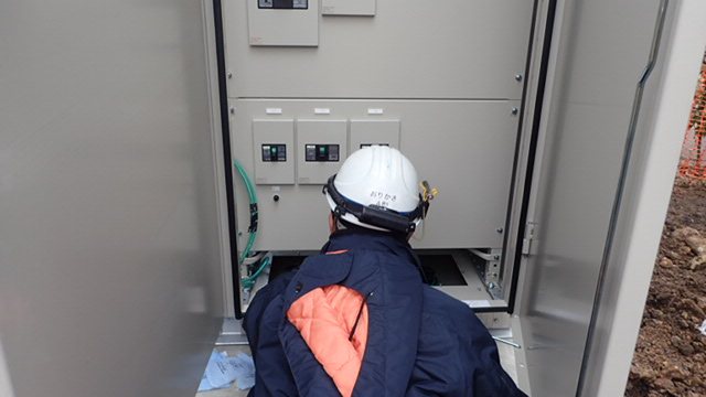 キュービクルの扉を開けて内部を確認する作業員