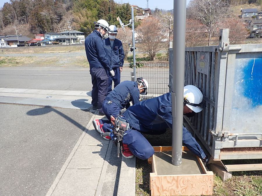 ポール基礎まわりで外灯の据付作業を行う作業員