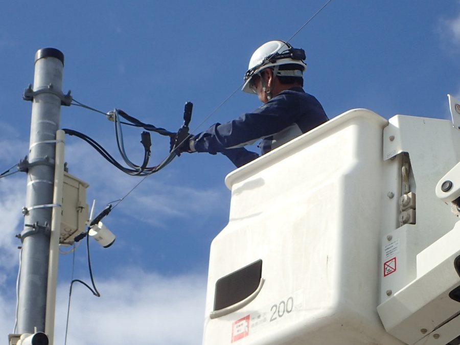 電柱上のバケットで幹線を接続する作業員