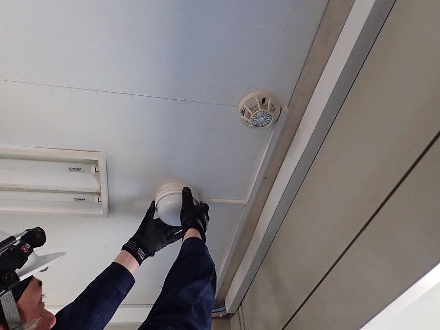 天井の火災感知器を取り付けている手元