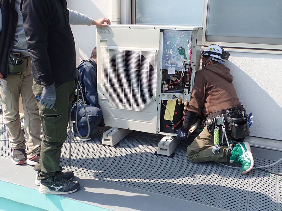 屋外機のカバーを外して配管接続を行う空調工事