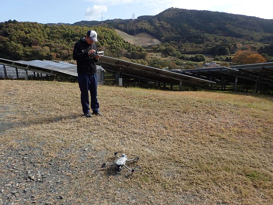 発電所の敷地でプロポを操作しドローンを飛ばす操縦者