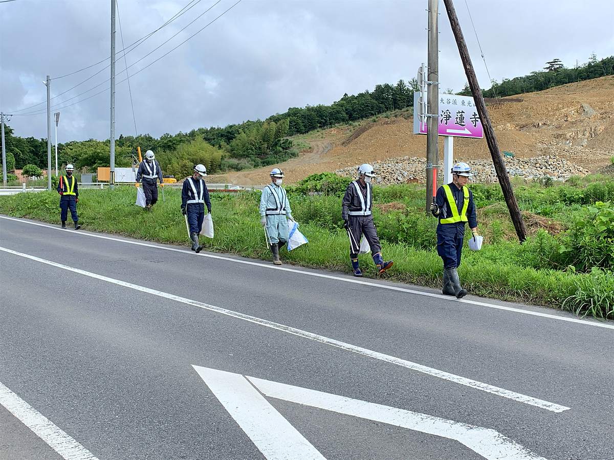 県道の路肩で安全ベストを着用して清掃活動を行う様子